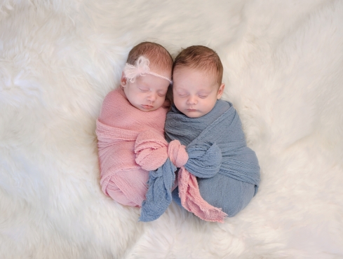 Dois bebês deitados, um de azul e o outro de rosa simbolizando o sexo do bebê